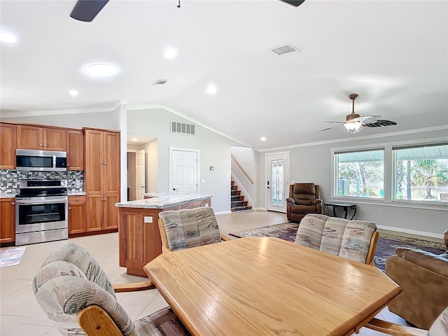 dining room with ceiling fan, light tile patterned floors, crown molding, and lofted ceiling