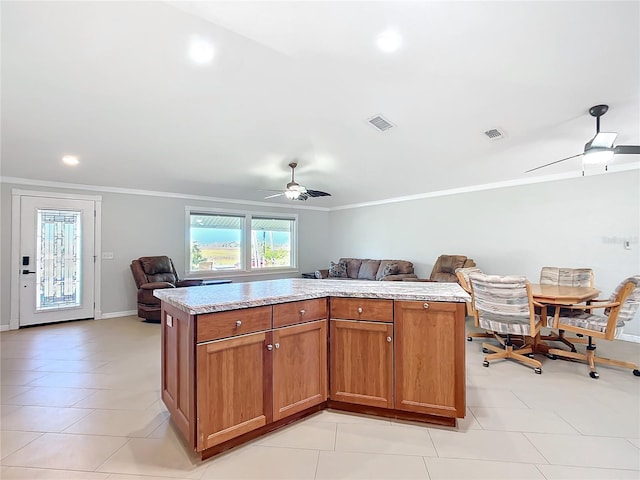 kitchen with crown molding, ceiling fan, and a kitchen island