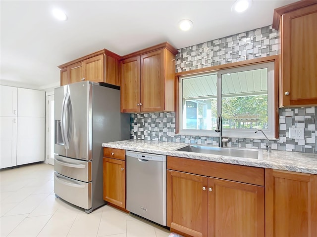 kitchen featuring sink, appliances with stainless steel finishes, tasteful backsplash, and light stone counters