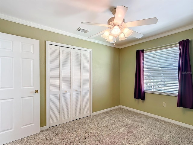 unfurnished bedroom with carpet, a closet, crown molding, and ceiling fan