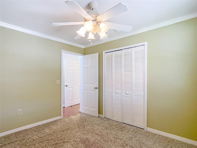 unfurnished bedroom featuring ceiling fan, a closet, crown molding, and carpet flooring