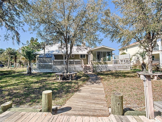 back of house featuring a yard, a wooden deck, and a sunroom