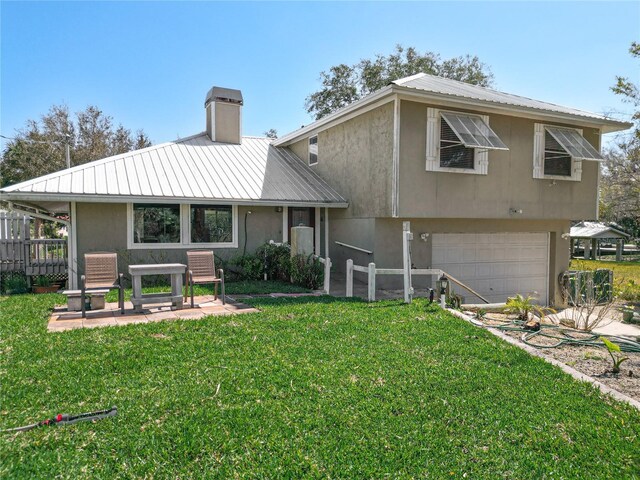 rear view of property with a garage and a lawn