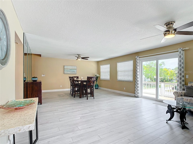 dining space with ceiling fan, light hardwood / wood-style floors, and a textured ceiling