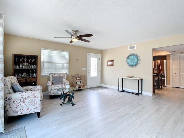 interior space featuring ceiling fan, light hardwood / wood-style flooring, and a textured ceiling