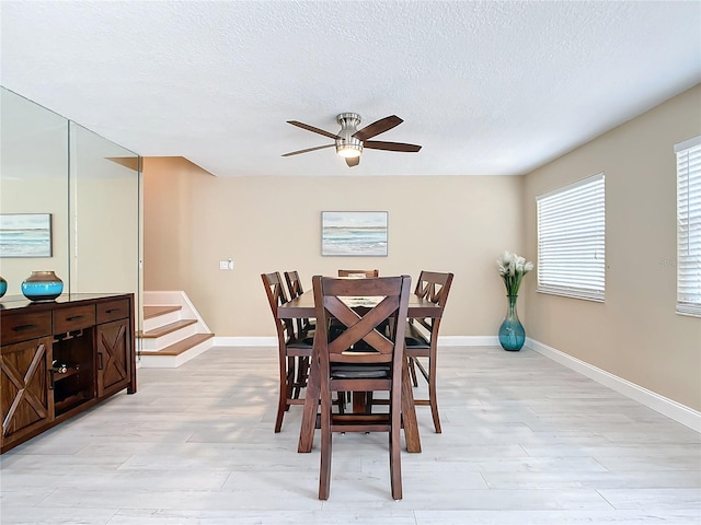 dining area with ceiling fan, light wood-type flooring, and a textured ceiling