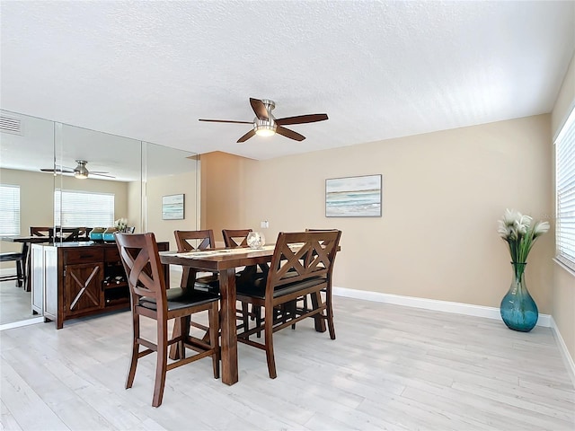 dining room with ceiling fan, light hardwood / wood-style floors, and a textured ceiling