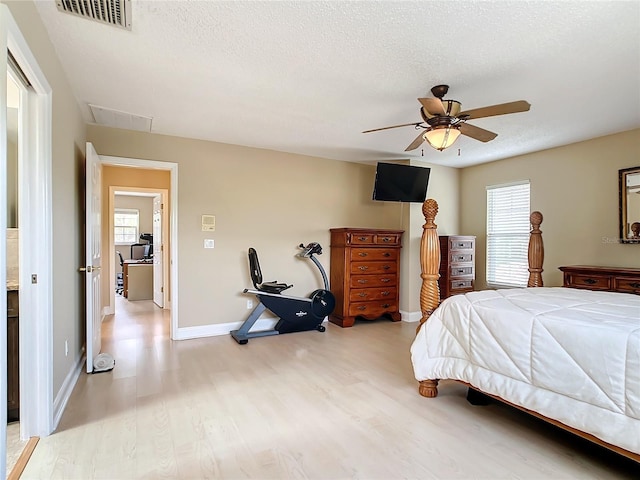 bedroom with ceiling fan, light hardwood / wood-style floors, and a textured ceiling