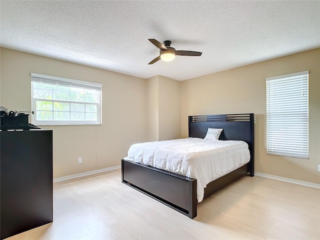 bedroom featuring ceiling fan, light hardwood / wood-style floors, and a textured ceiling