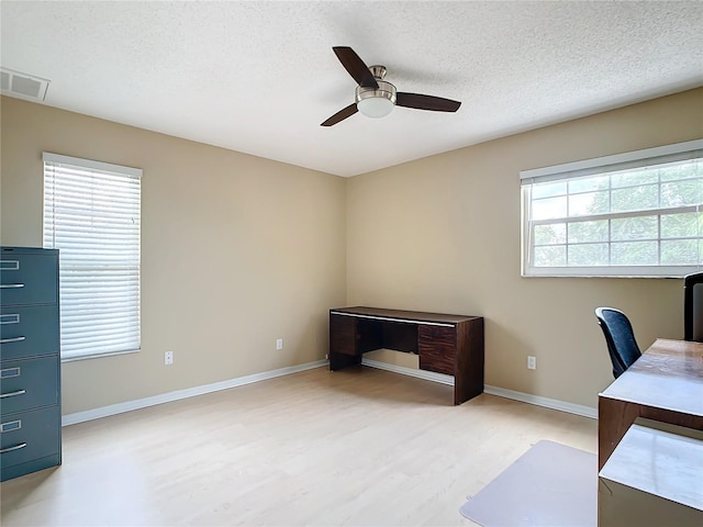 unfurnished office with plenty of natural light, ceiling fan, light hardwood / wood-style floors, and a textured ceiling