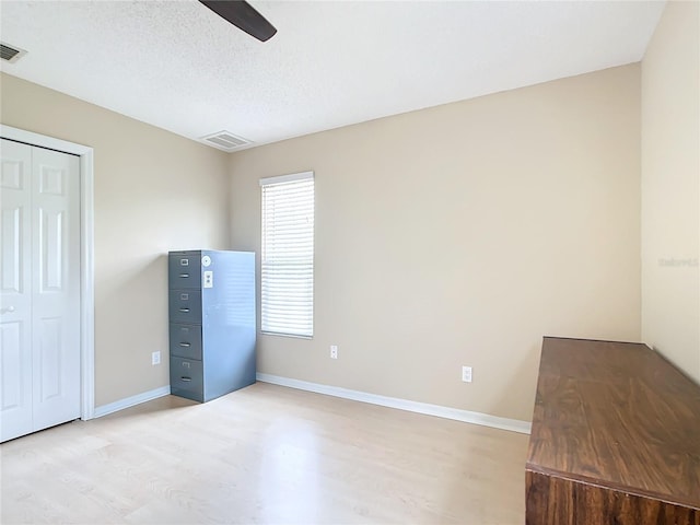 unfurnished bedroom with a closet, ceiling fan, light hardwood / wood-style flooring, and a textured ceiling