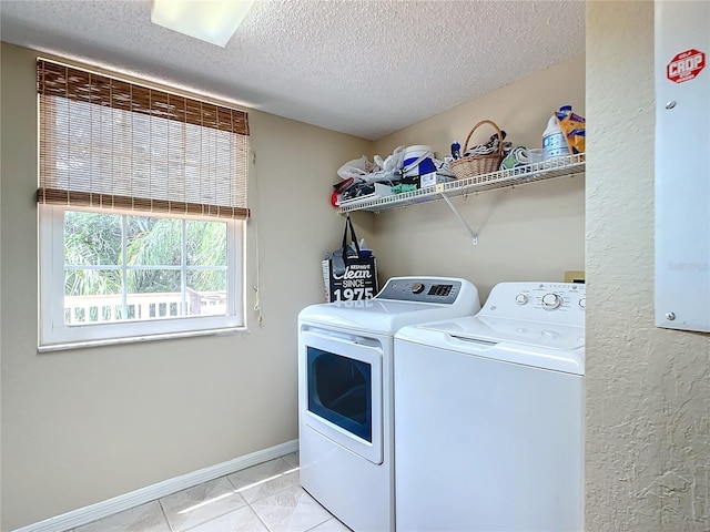 clothes washing area with independent washer and dryer, a textured ceiling, and light tile patterned floors