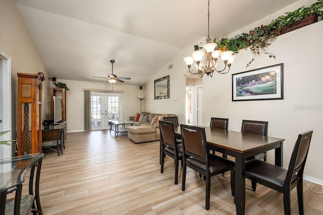 dining space with ceiling fan with notable chandelier, french doors, lofted ceiling, and light hardwood / wood-style flooring