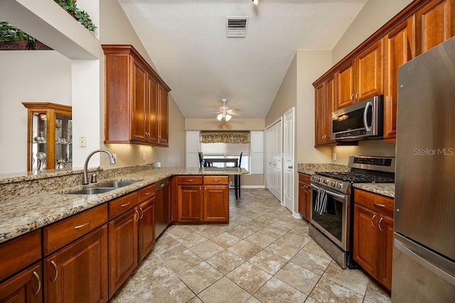 kitchen featuring kitchen peninsula, light stone countertops, appliances with stainless steel finishes, ceiling fan, and sink