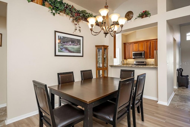 dining area featuring light wood-type flooring, a chandelier, and sink