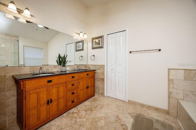 bathroom featuring tile walls, a bathing tub, and vanity