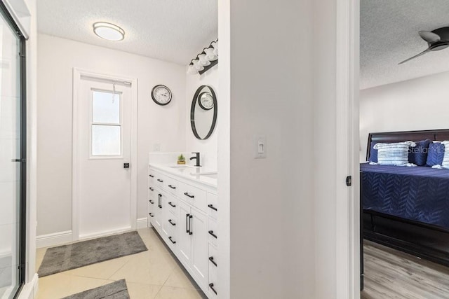 bathroom featuring ceiling fan, tile patterned flooring, vanity, and a textured ceiling