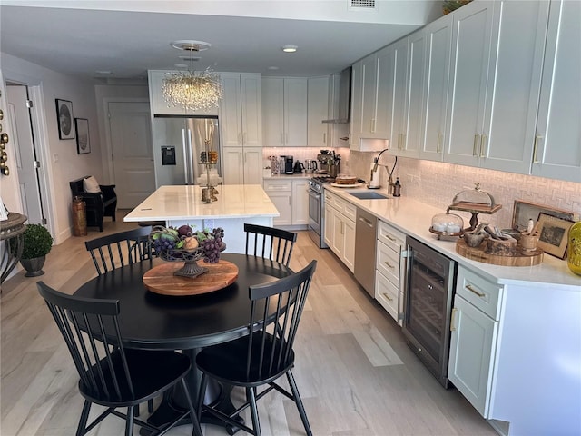 kitchen featuring white cabinetry, sink, beverage cooler, and appliances with stainless steel finishes