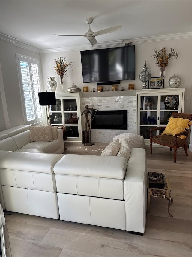 living room featuring light hardwood / wood-style flooring, ornamental molding, a tile fireplace, and ceiling fan