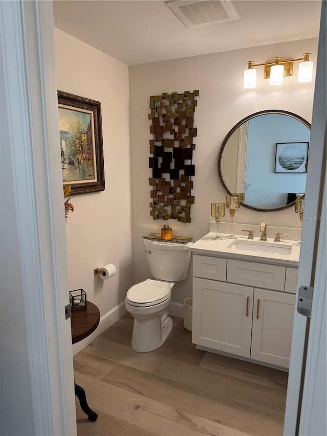 bathroom with wood-type flooring, vanity, and toilet