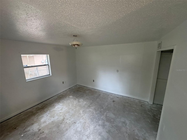 spare room featuring a textured ceiling and concrete flooring