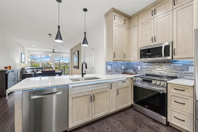 kitchen with hanging light fixtures, sink, appliances with stainless steel finishes, tasteful backsplash, and kitchen peninsula