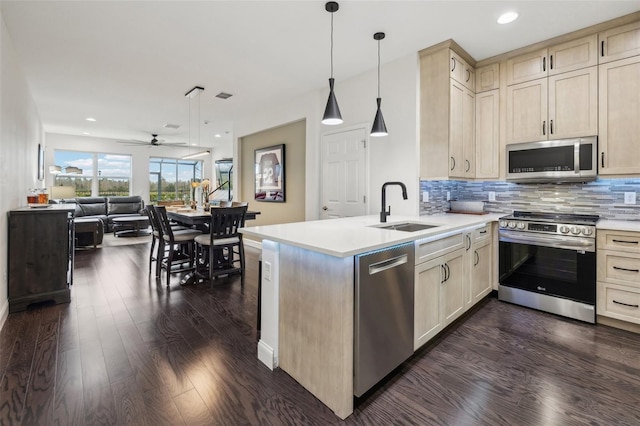 kitchen featuring ceiling fan, sink, hanging light fixtures, decorative backsplash, and appliances with stainless steel finishes