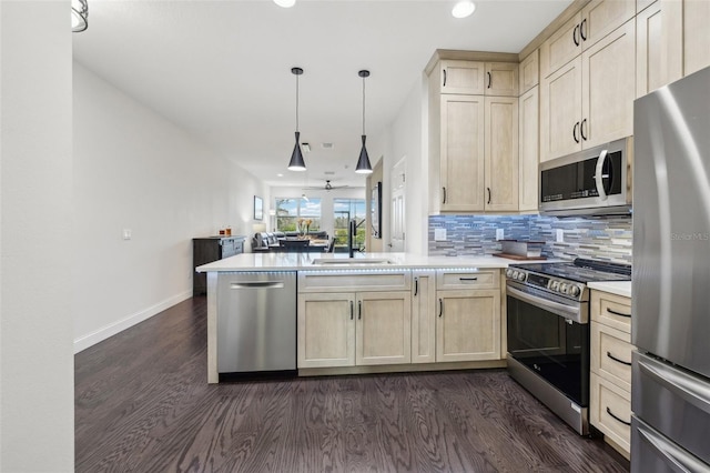 kitchen featuring hanging light fixtures, sink, appliances with stainless steel finishes, tasteful backsplash, and kitchen peninsula