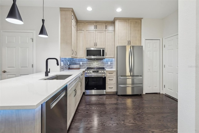 kitchen featuring kitchen peninsula, appliances with stainless steel finishes, backsplash, sink, and pendant lighting