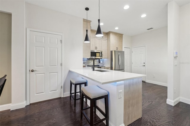 kitchen featuring pendant lighting, sink, appliances with stainless steel finishes, a kitchen bar, and kitchen peninsula