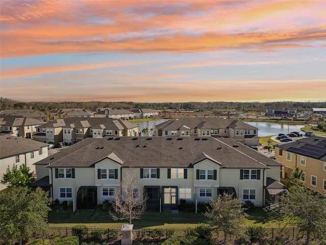 aerial view at dusk featuring a water view