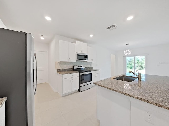 kitchen featuring stainless steel appliances, sink, white cabinetry, tasteful backsplash, and light stone countertops