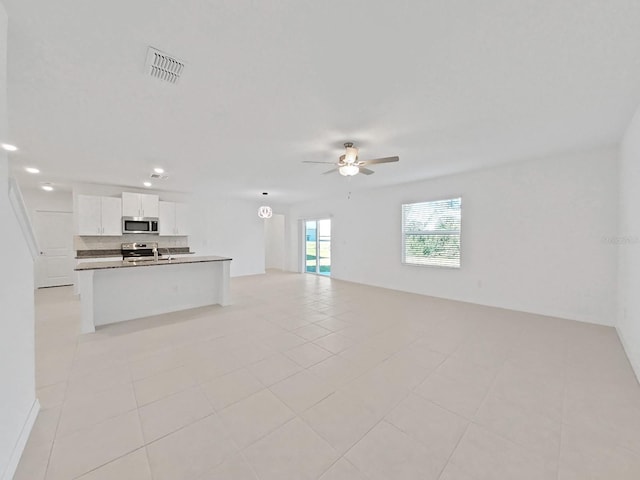 unfurnished living room featuring light tile patterned flooring and ceiling fan