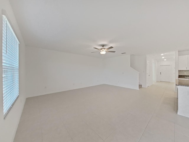 tiled spare room featuring ceiling fan