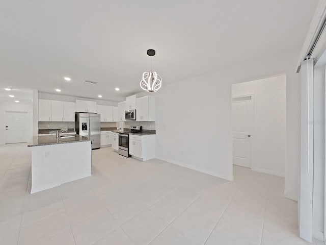 kitchen featuring stainless steel appliances, a center island with sink, light tile patterned floors, and white cabinetry