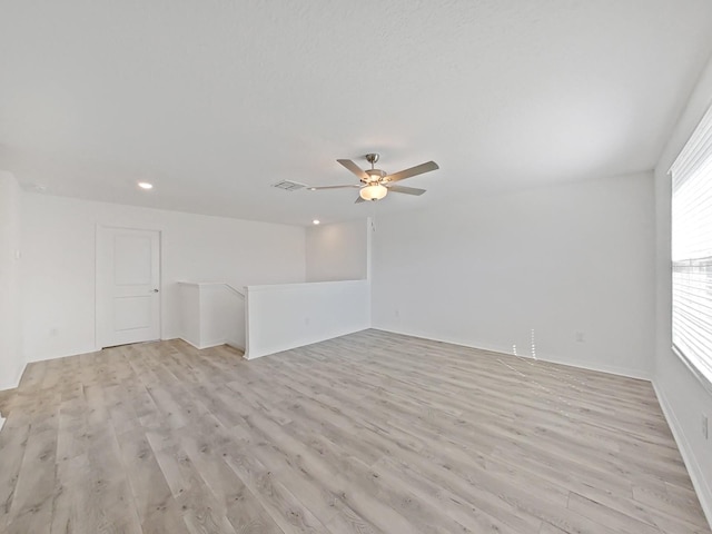 spare room with ceiling fan, light wood-type flooring, and a wealth of natural light