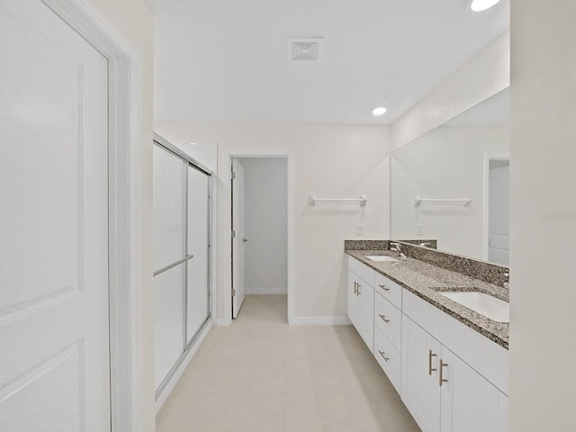 bathroom with a shower with door, vanity, and tile patterned flooring