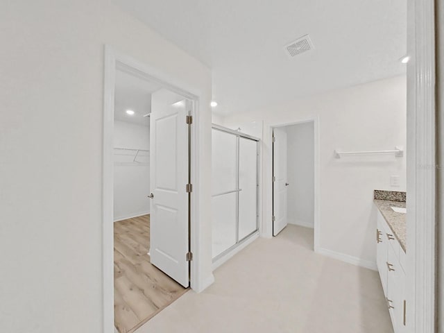 bathroom featuring a shower with door and vanity