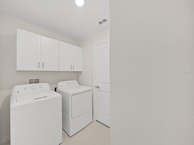 clothes washing area featuring washing machine and dryer and cabinets