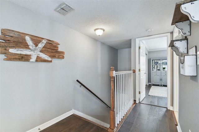 hall with a textured ceiling and dark wood-type flooring