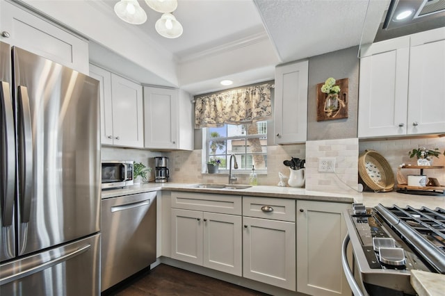 kitchen featuring light stone counters, ornamental molding, stainless steel appliances, sink, and white cabinets