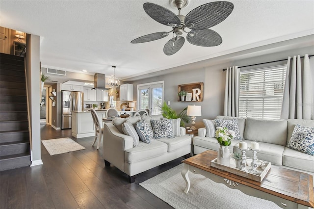 living room with a textured ceiling, crown molding, dark wood-type flooring, and ceiling fan with notable chandelier