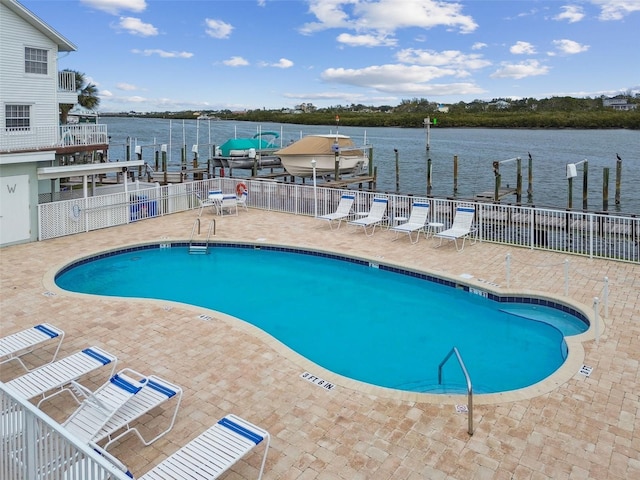 view of pool featuring a boat dock, a patio, and a water view