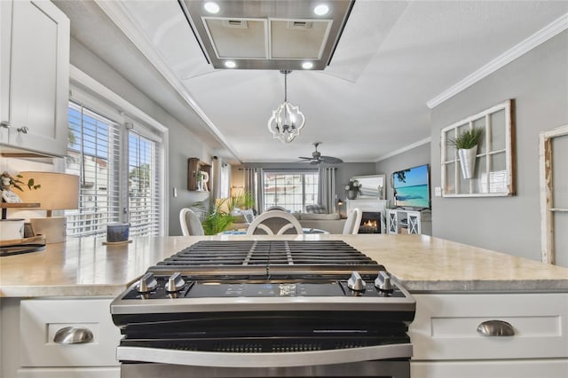 kitchen featuring white cabinets, ceiling fan, ornamental molding, decorative light fixtures, and stainless steel range with gas stovetop