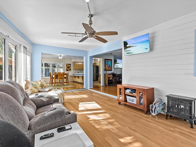 living room featuring ceiling fan, wood-type flooring, and wooden walls