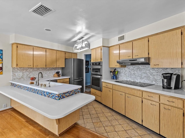 kitchen with tasteful backsplash, kitchen peninsula, sink, and stainless steel appliances