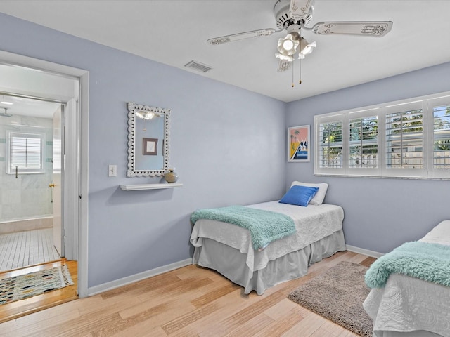 bedroom with ceiling fan, wood-type flooring, connected bathroom, and multiple windows