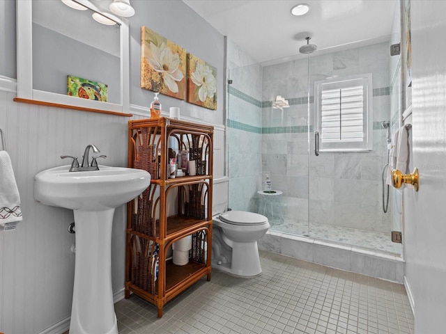 bathroom with tile patterned floors, toilet, a shower with door, and sink