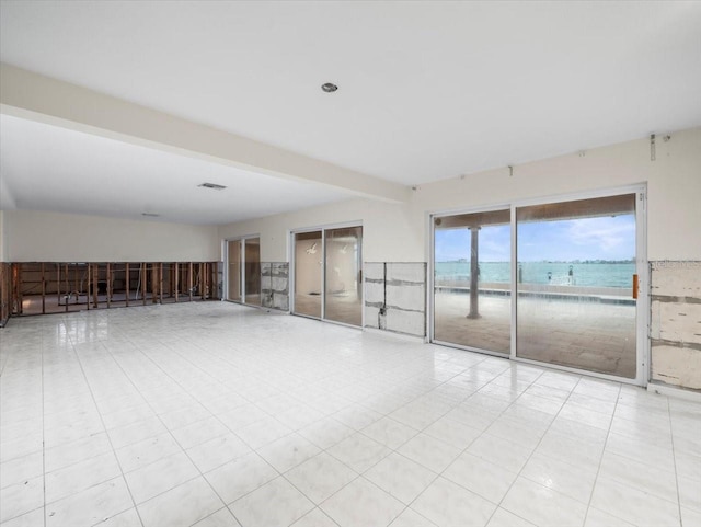 spare room featuring a water view and beamed ceiling