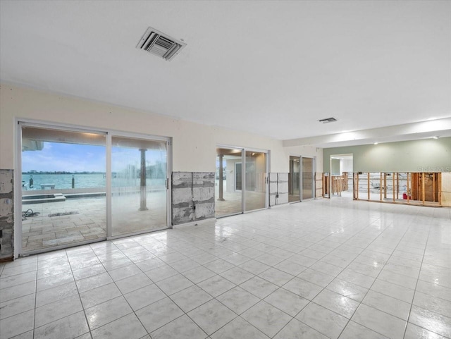 spare room featuring a water view and light tile patterned floors